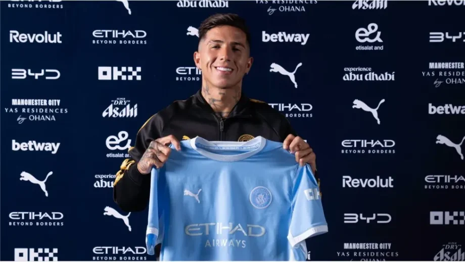 Enzo Fernandez holds up his Man City shirt