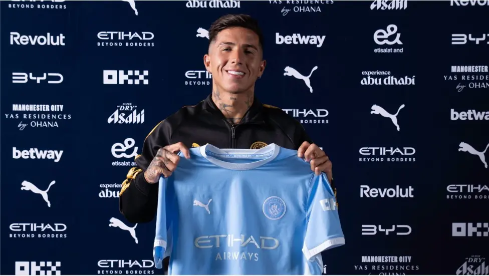 Enzo Fernandez holds up his Man City shirt